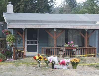 Flowers are placed outside the police tape at the home on Morgan Street in Black Diamond where 86-year-old Ella May Walker was stabbed to death Friday