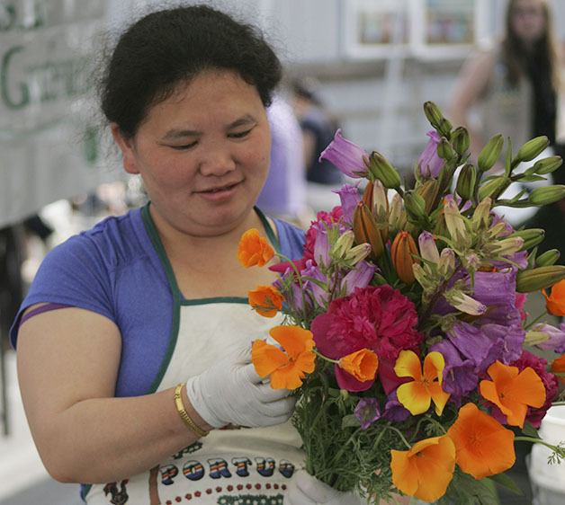 See Xiong prepares a bouquet of flowers Saturday on the opening day of the Maple Valley Farmers Market.