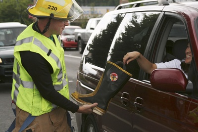 Firefighter Mike Ager holds the boot for a donation Friday at the intersection of Kent Kangley Road and state Route 169.