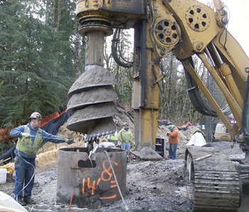 In March workers drill 55-foot shafts deep into the bedrock to support the bridge from land movement.