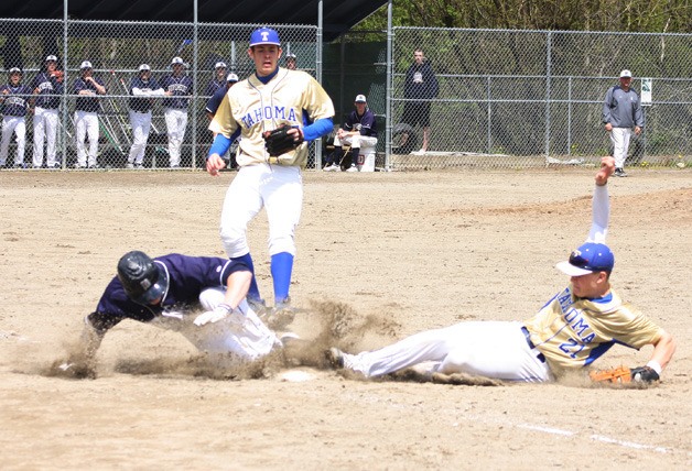 Tahoma first baseman Tanner Anthony slides to first trying to get the Auburn Riverside runner out. The base runner was called safe. Pitcher Chris Kerwood is in the background.