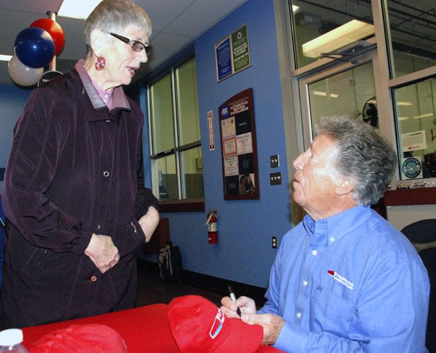 Mario Andretti signs a hat for Covington Mayor Margaret Harto after the grand opening ceremony for the new Firestone store in Covington.