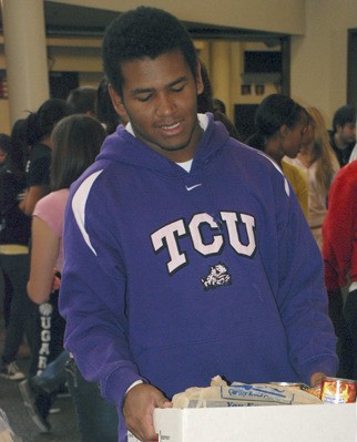 Kentwood's Joesph Banks carries a box of food to the Munch Madness weigh-in event Monday