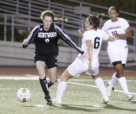 Kentwood midfielder Kiana Kraft takes a pass and trips up Kentlake midfielder Leanna McCord as they fight for possession on Tuesday. Kraft led the Conquerors with both goals in the second half to beat the Falcons 2-0.