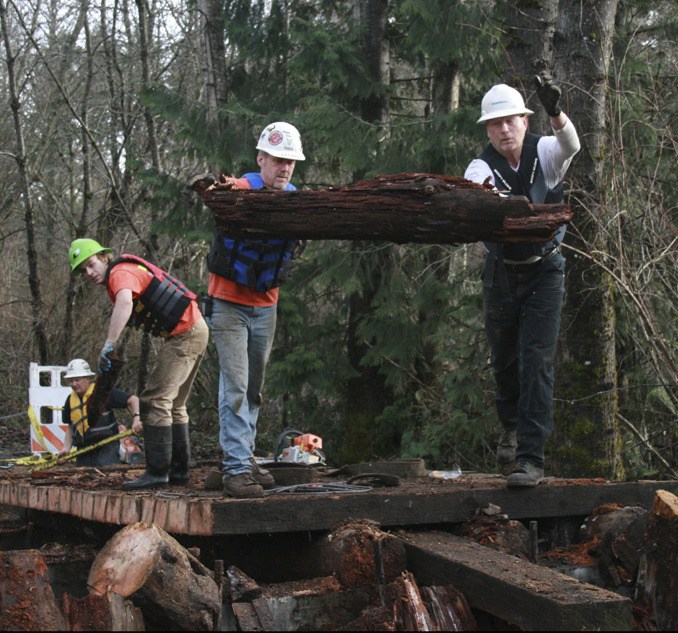 Rod Scott and Leon Breland with R.W. Scott Construction remove the busted Jenkins Creek Bridge pieces Thursday