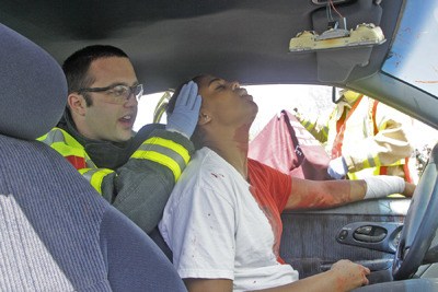 Kent Fire Fighter Alex Richardson holds up the head of Lychelle Roberts-Kirby as Kent Fire prepares to pull off the door to get her out during the reenactment of a car crash. The reenactment was part of the Fire Department Gift of Life presentation at Kentwood High School Thursday