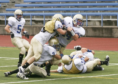 Zach Browne is tackled after a long run by Matt Stubbles and Justin Ross. Jake Akins looks on.